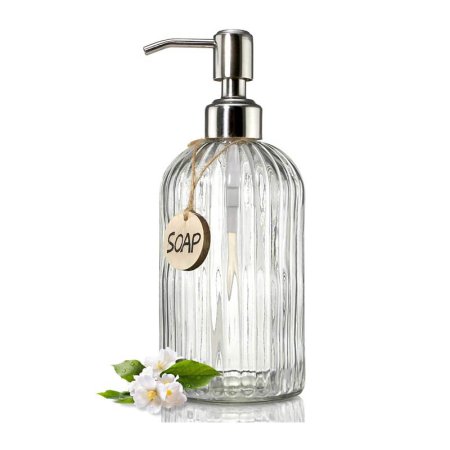  The Jasai 18-Ounce Clear Glass Soap Dispenser on a white background next to a small cluster of flowers.