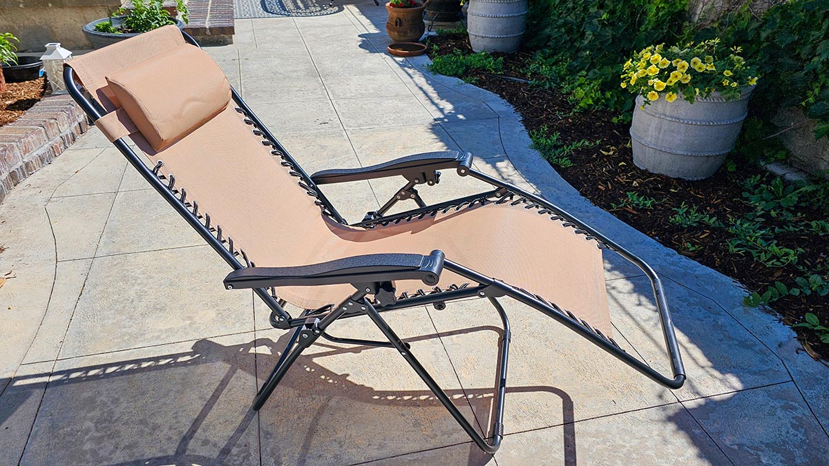 Black and tan zero gravity chair reclined on concrete patio