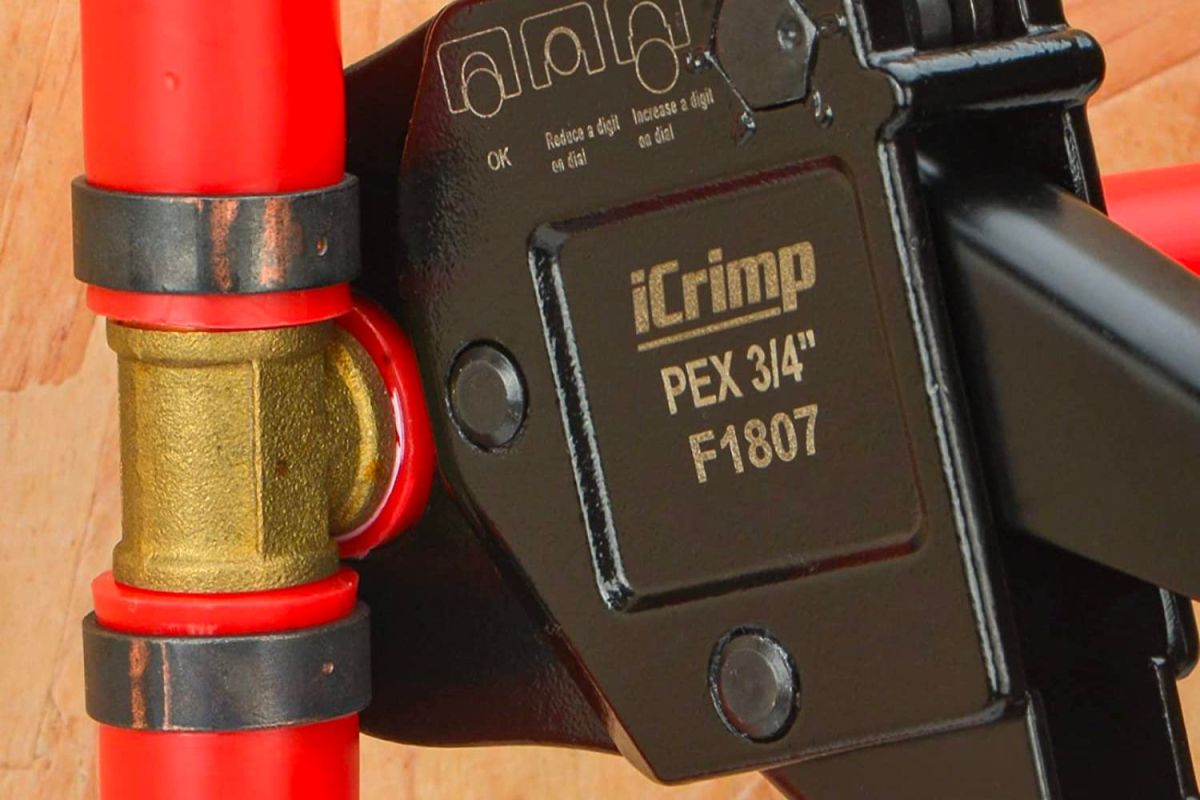 Closeup of an iCrimp PEX crimp tool being used on a red pipe