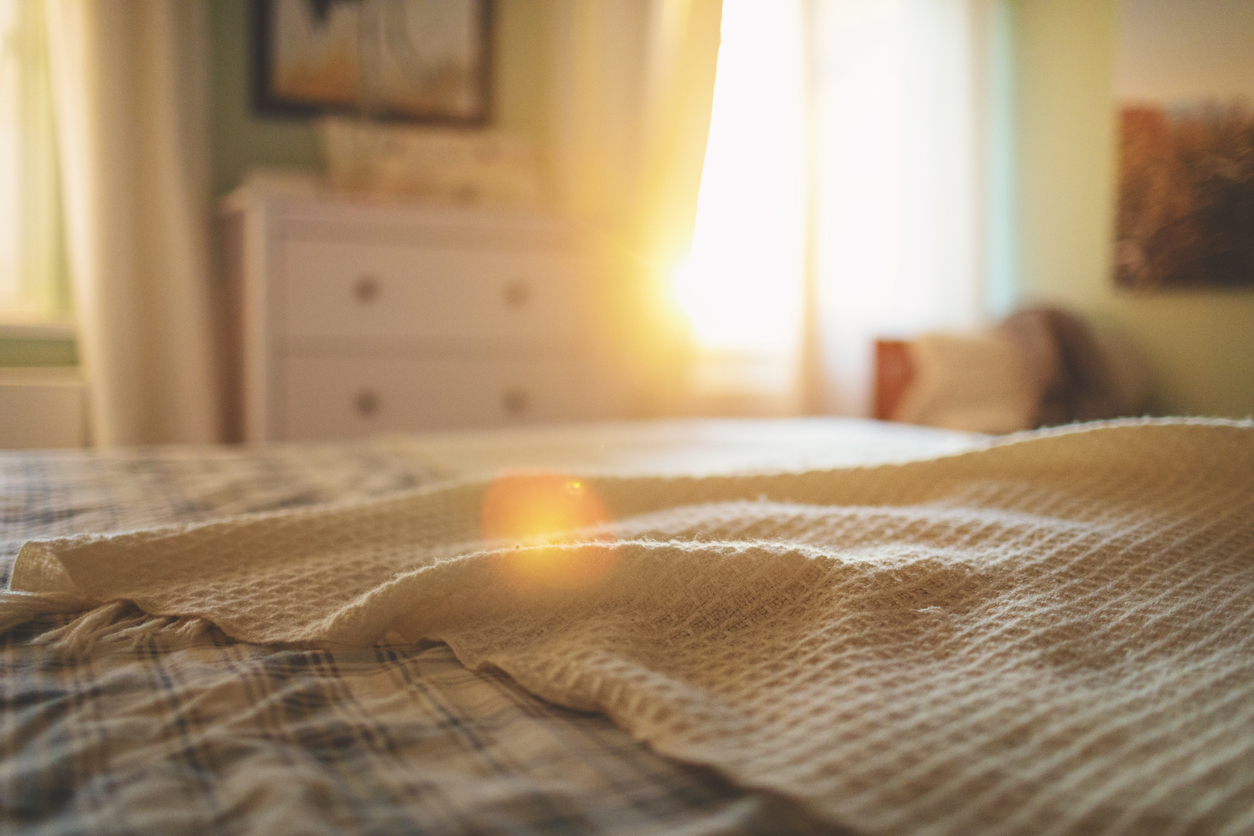 bedroom with bed in foreground and sunlight streaming through window