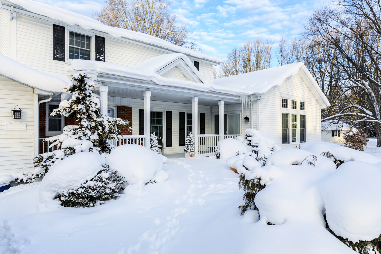 white house covered in snow with icicles hanging from porch