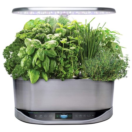  The AeroGarden Bounty Elite Indoor Garden full of growing plants under a bright grow light.