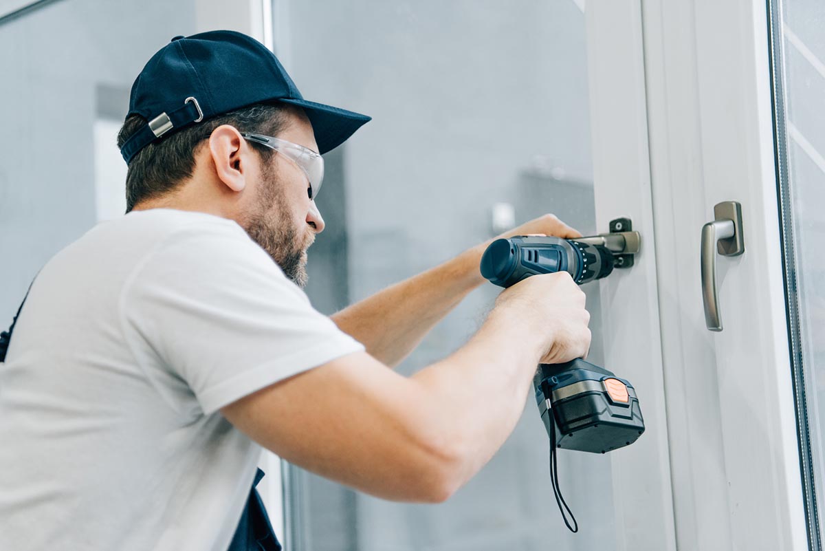 A worker drills into a white door. 