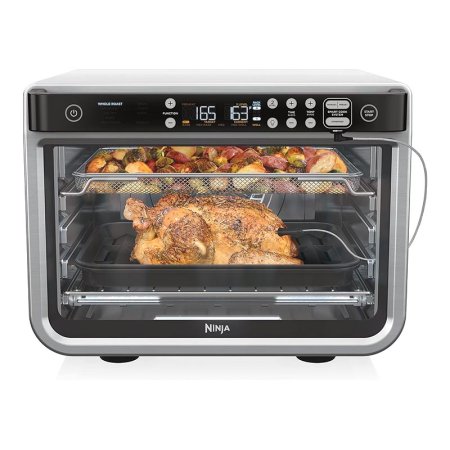  The Ninja Foodi Smart XL Pro Air Oven cooking a whole chicken and a tray of vegetables.