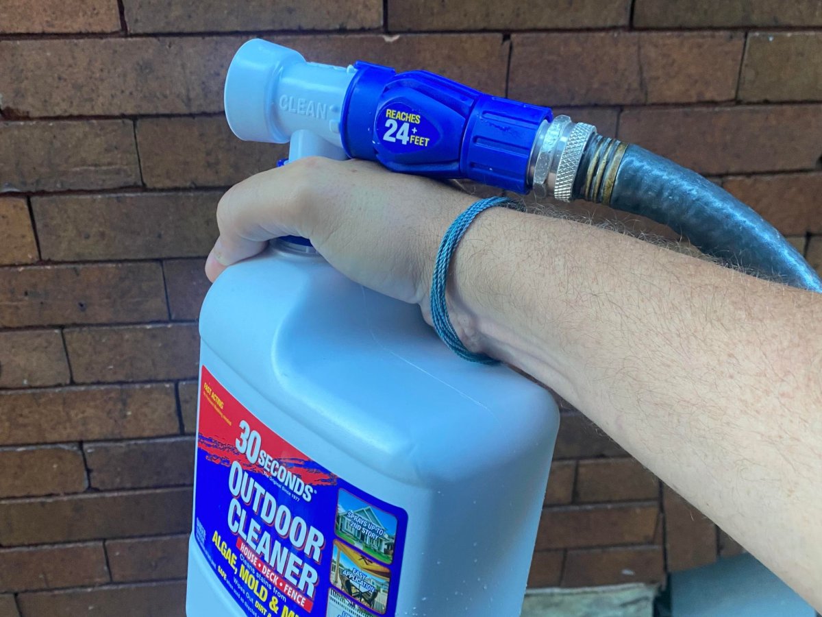 man holding and spraying the roof cleaner on tiles 