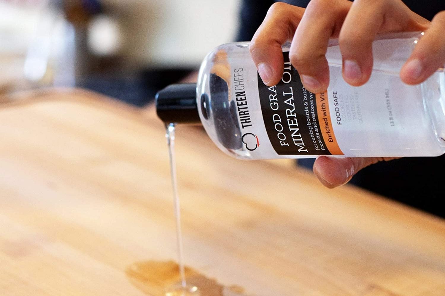 A person pouring Thirteen Chefs Food Grade Mineral Oil on a cutting board to treat and maintain it.