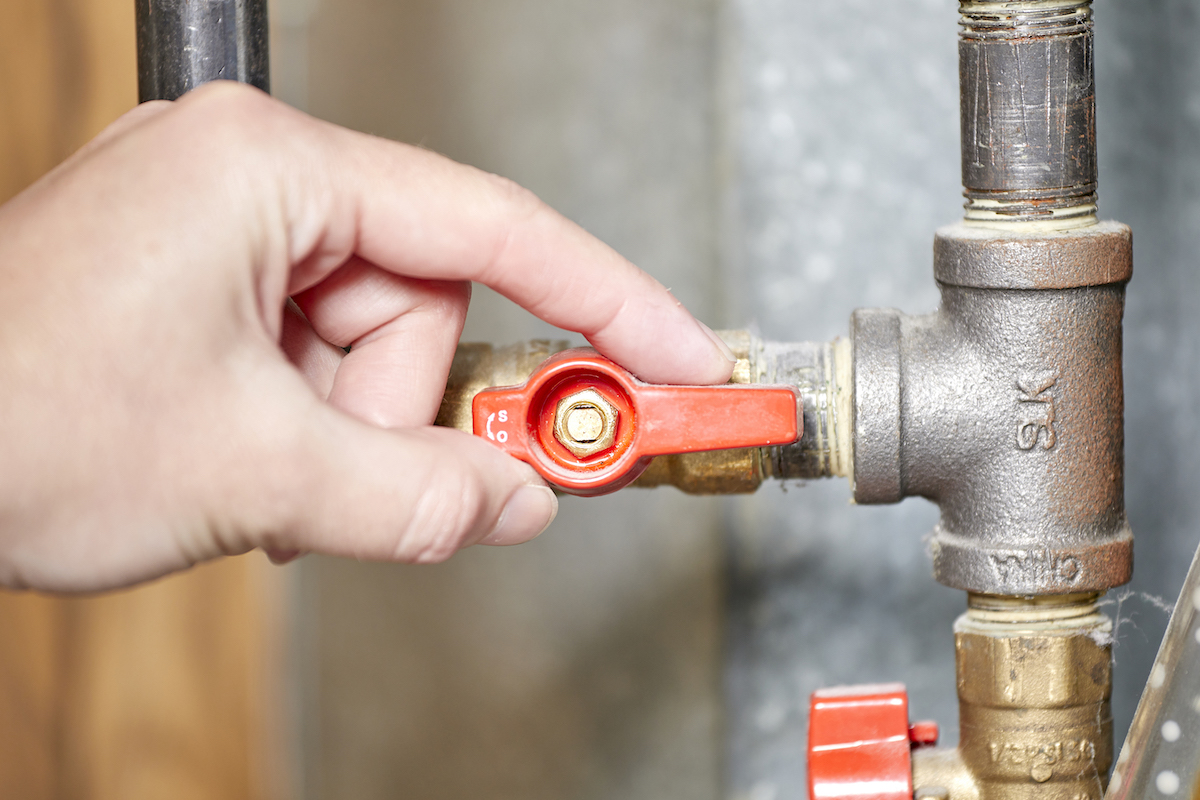 Woman turns a red gas valve to the open position.