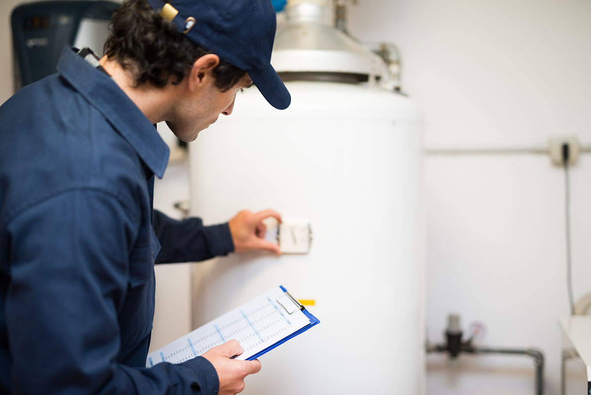 A worker assesses a water heater's function.