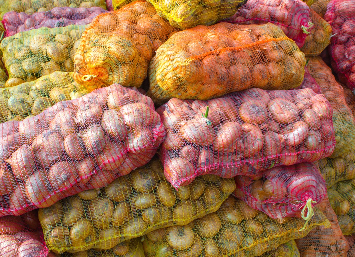 onions-in-yellow-and-pink-plastic-mesh-sacks-picture-id905268184