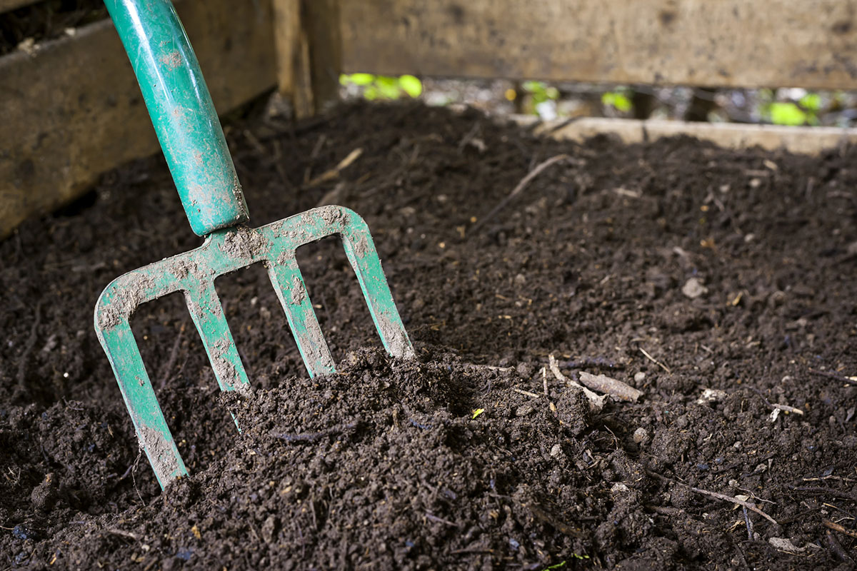 A close up of topsoil and a teal hand tool.