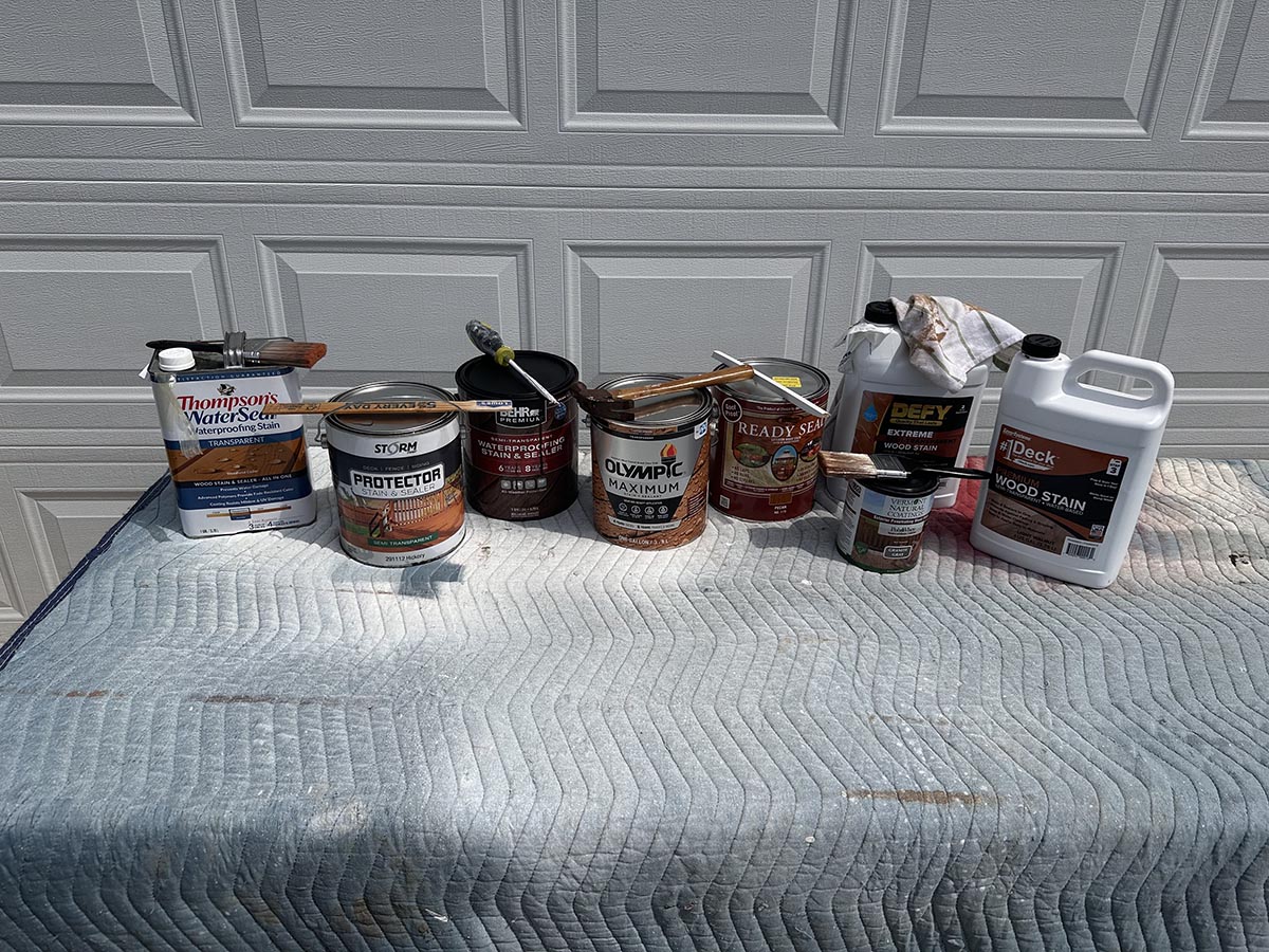 A group of the best exterior wood stains in front of a garage door before testing.