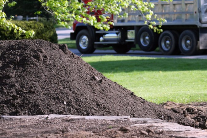 A mound of dirt is on a green lawn.