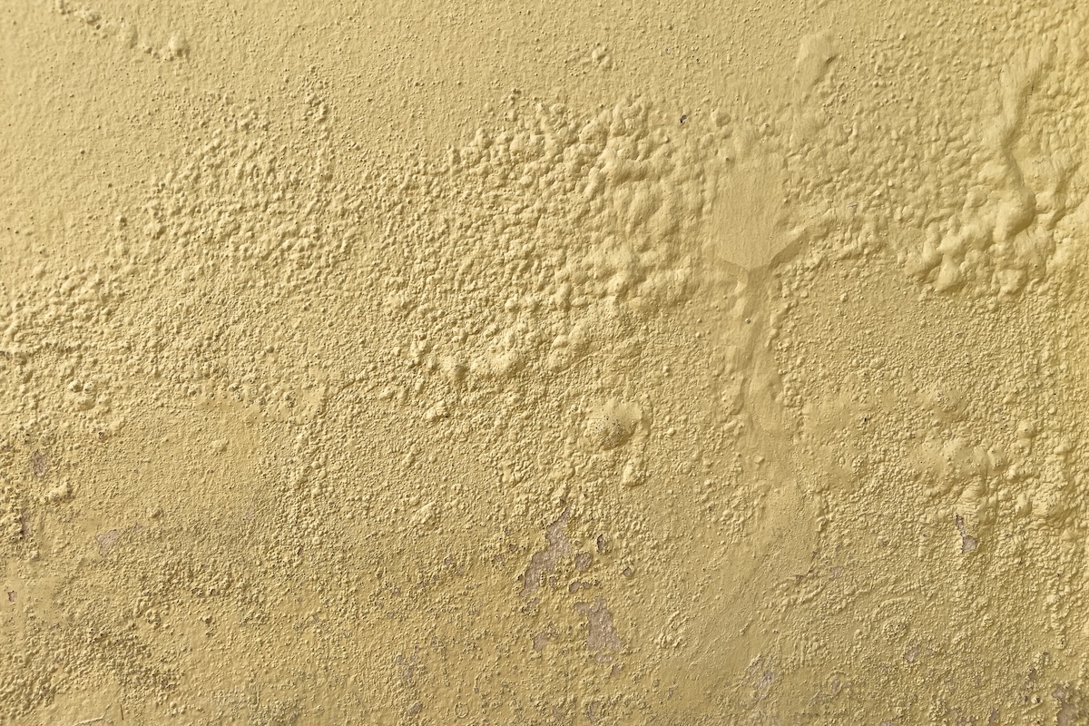 A yellow wall with bubbling yellow paint. 