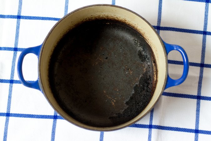 Burned enamel kitchen pot on a blue and white tablecloth