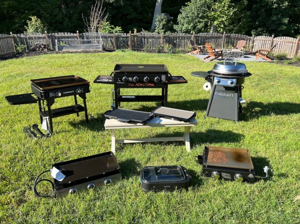 8 flat top grills lined up outdoors on a lawn