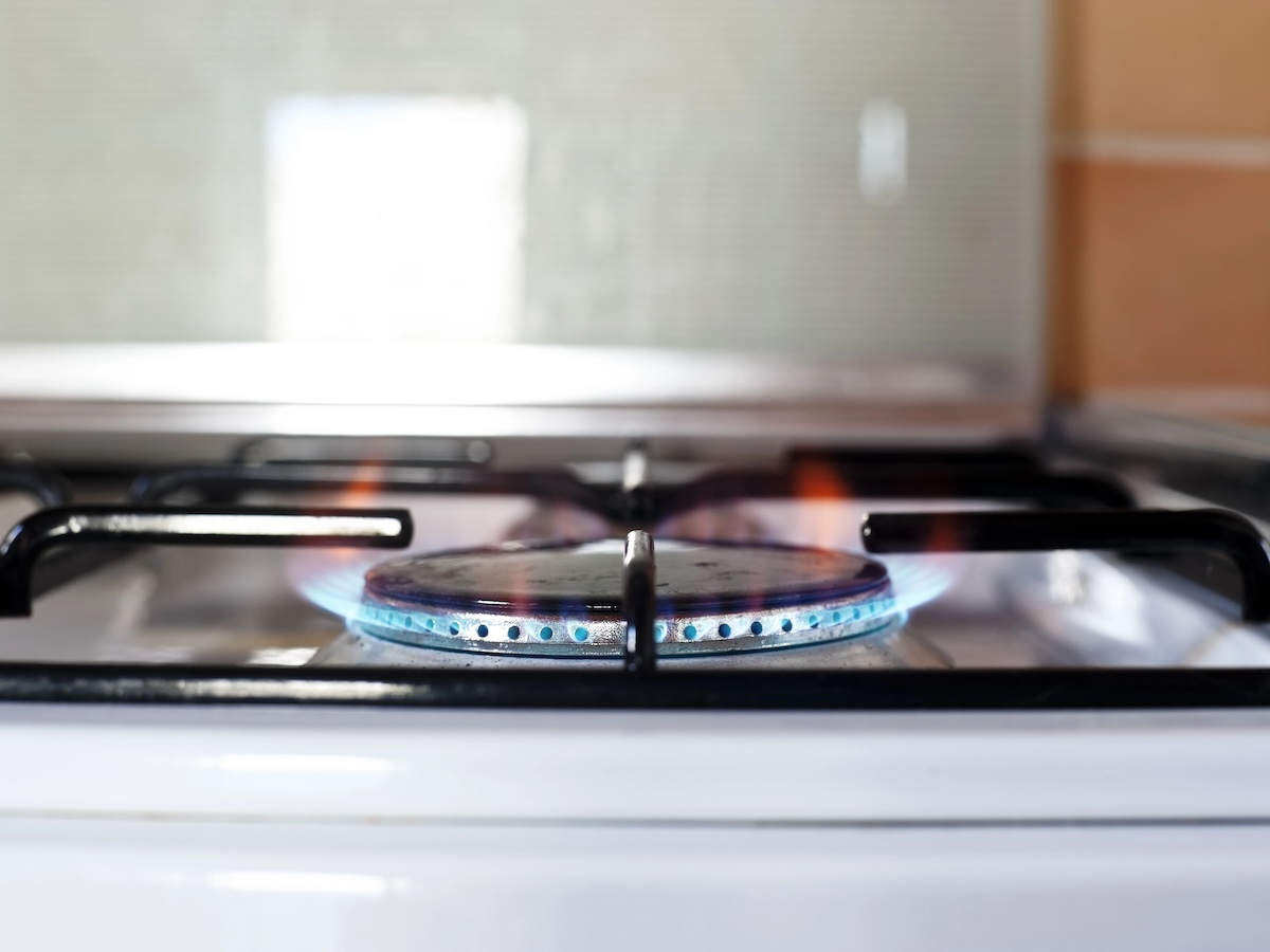 A gas range burner near a painted wall.