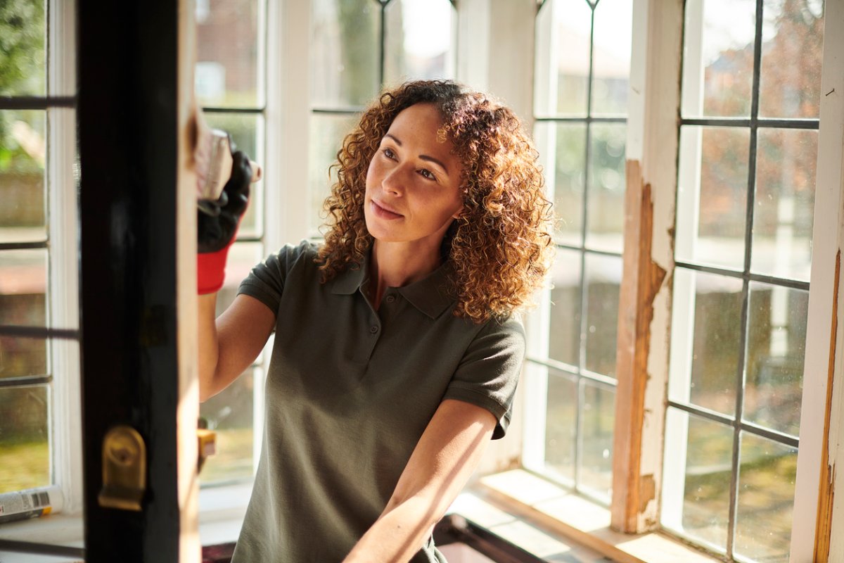 Woman with curly hair painting front door black