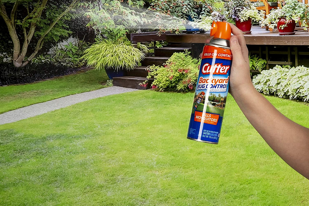 A can of Cutter bug control spray being sprayed on a lawn