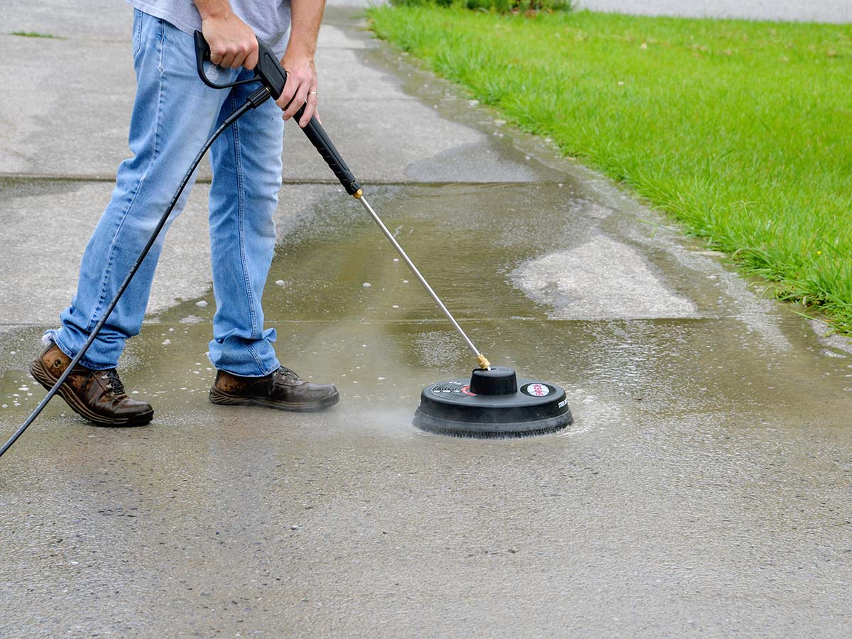 Man washing a driveway with a pressure washer