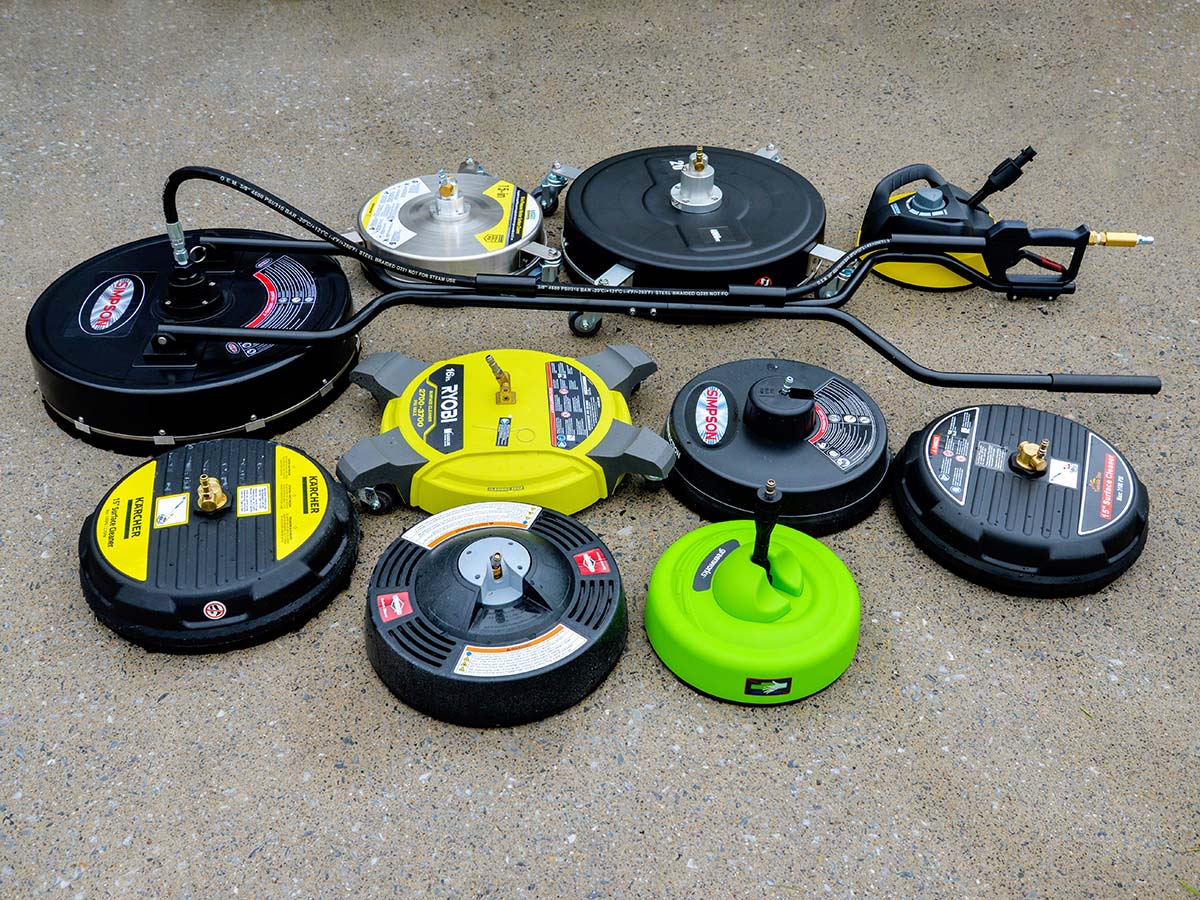 Multiple pressure washer surface cleaners lined up on a concrete slab