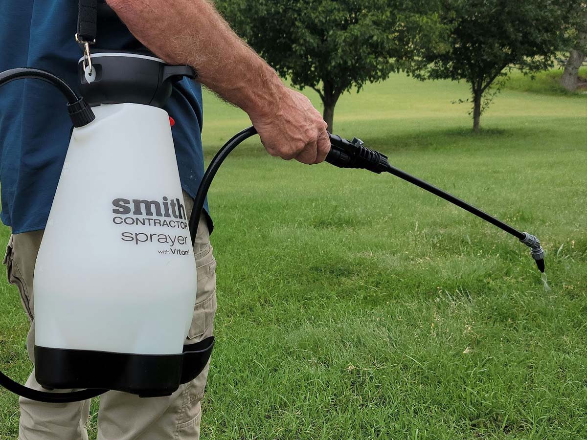 Man using a pump sprayer on a lawn