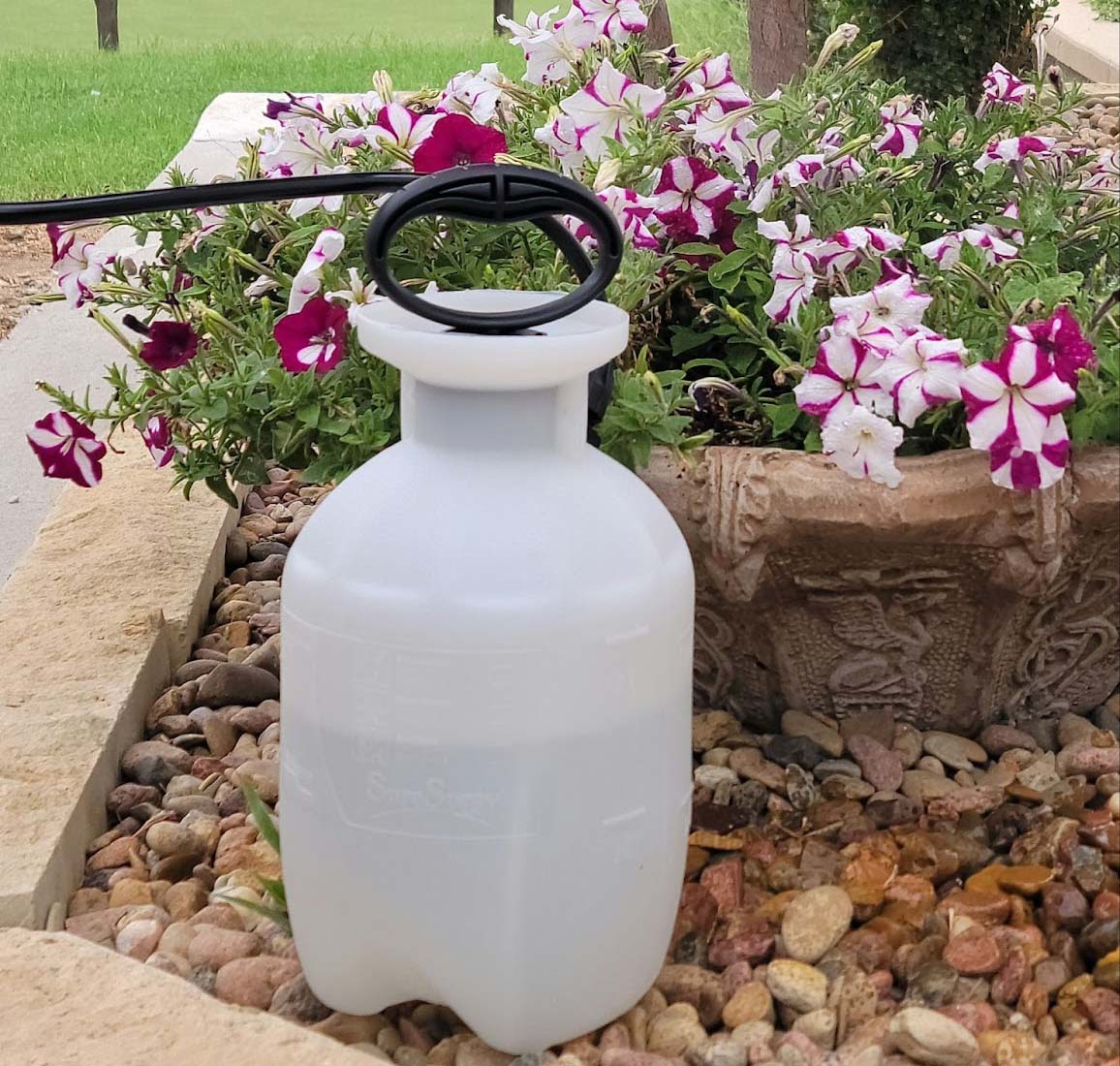 Pump sprayer on gravel next to a planter