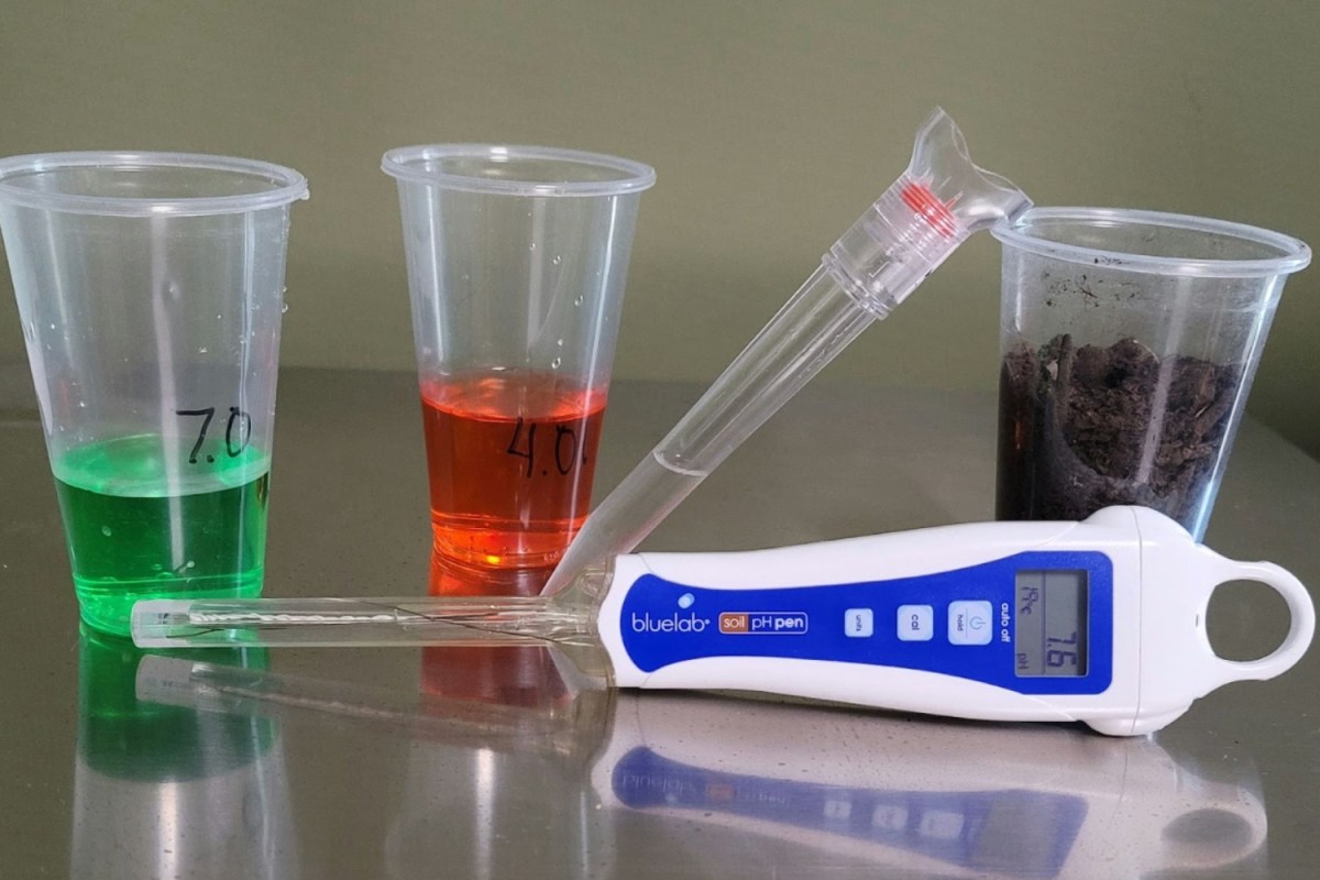 Soil test kit on a table next to 3 test tubes with colored liquids