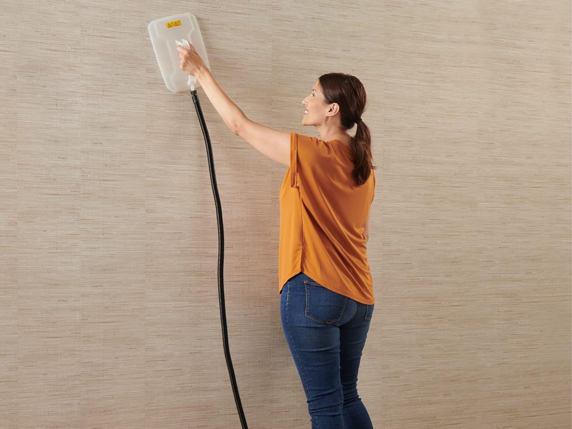 a woman using one of the best wallpaper remover in the living room