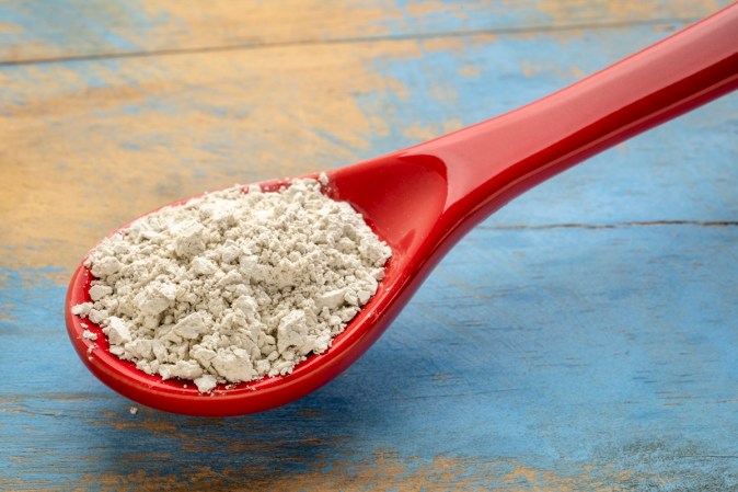 Red spoon full of diatomaceous earth.