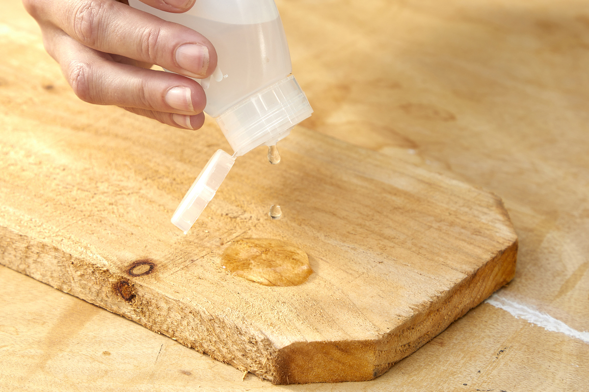 Woman uses a small squirt bottle to squirt a few drops of water on pressure-treated wood.