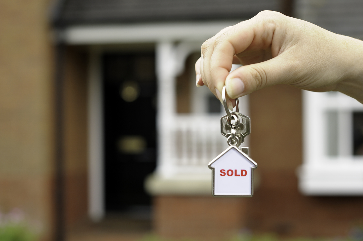 New home concept portrayed by a female holding front door keys in front of a newly built house.