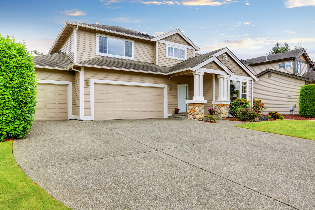 A concrete driveway in front of a two-story vinyl-sided house.