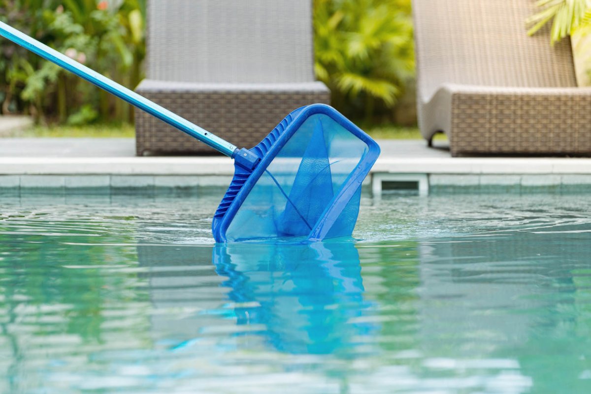 A blue pool net skimming a swimming pool as part of routine maintenance.