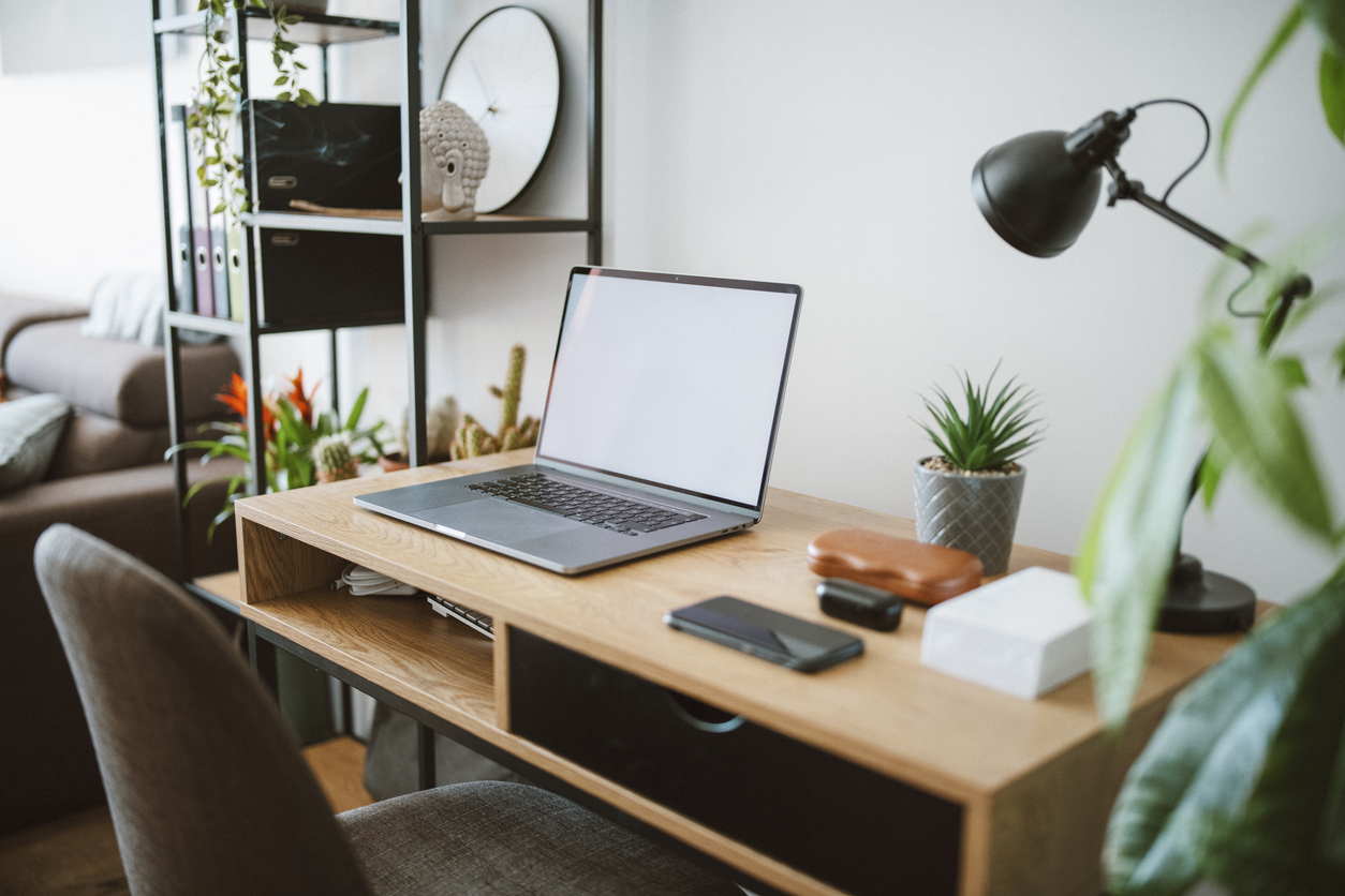 A shot of a laptop on top of a desk in a empty home office.