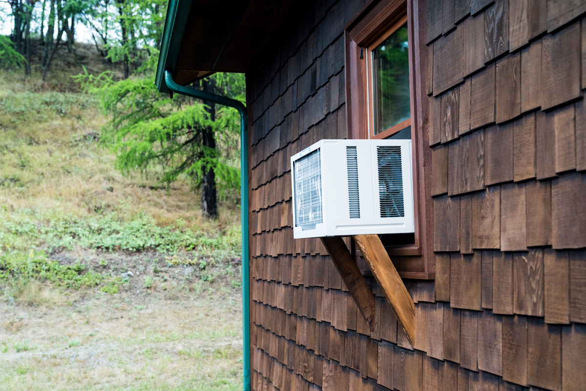 A window air conditioning unit is supported by brackets.