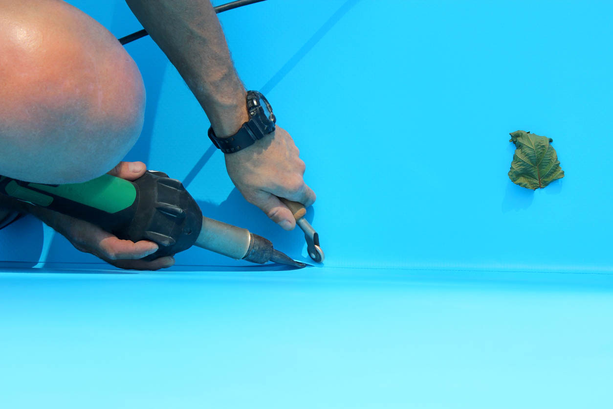 A worker fixes a leak in a pool liner.