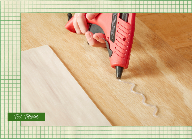 A DIYer using a glue gun on a piece of plywood with a graphic overlay that says Tool Tutorial.