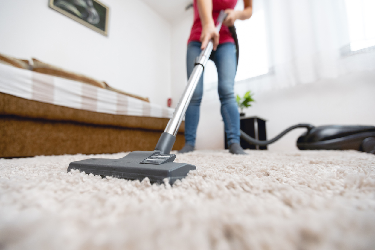 Young woman using vacuum cleaner to clean the house