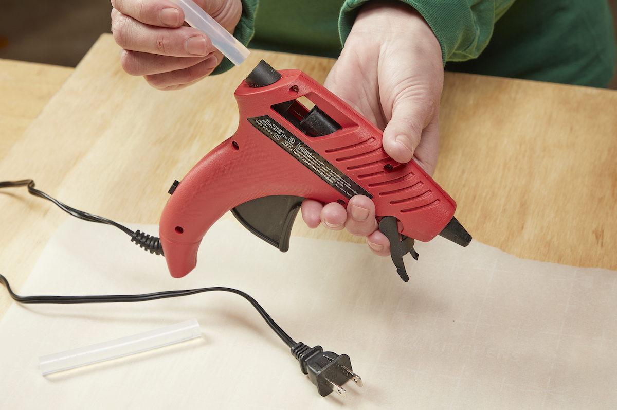 Woman loads a glue stick into a hot glue gun.