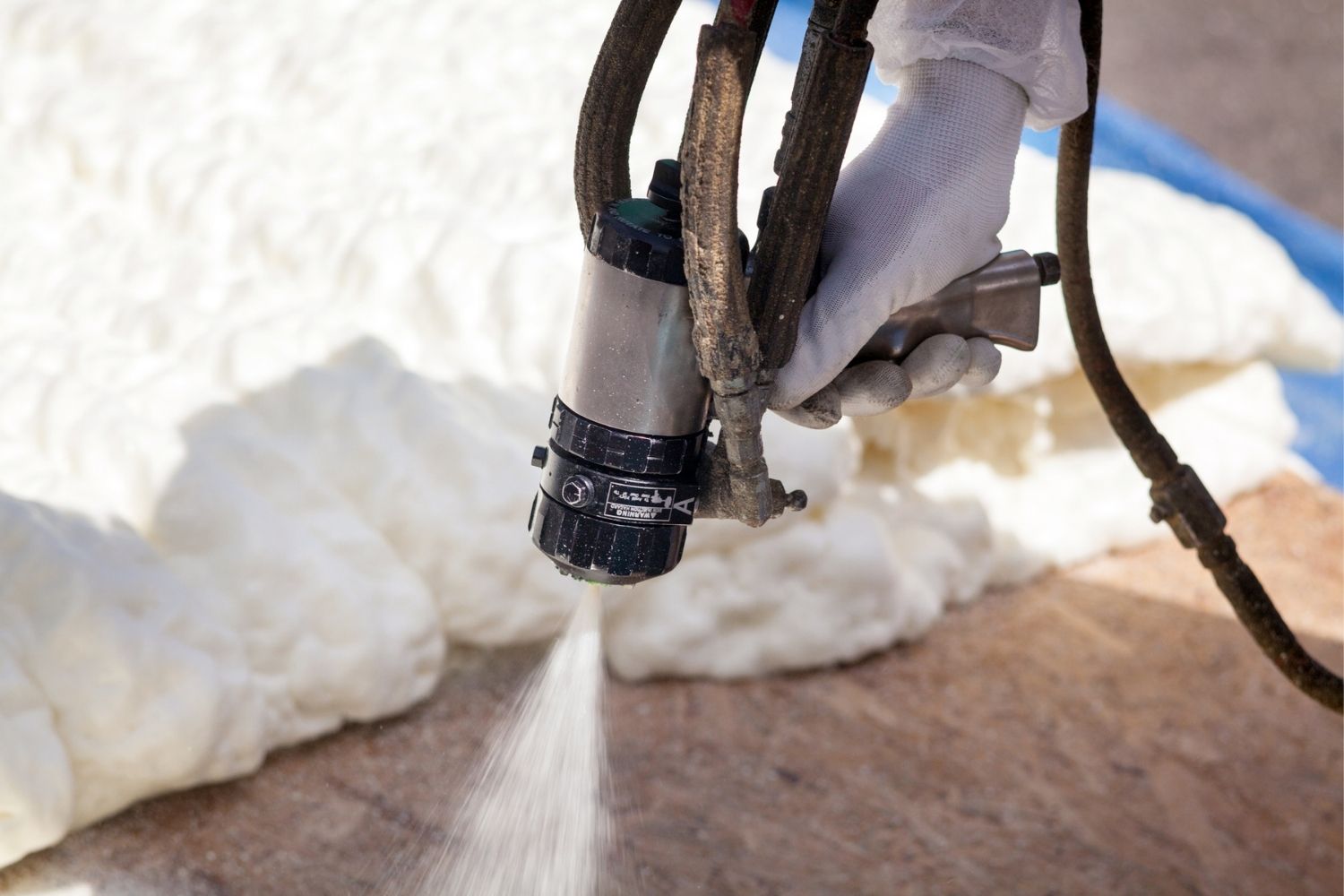 A close-up of a worker applying spray foam insulation.