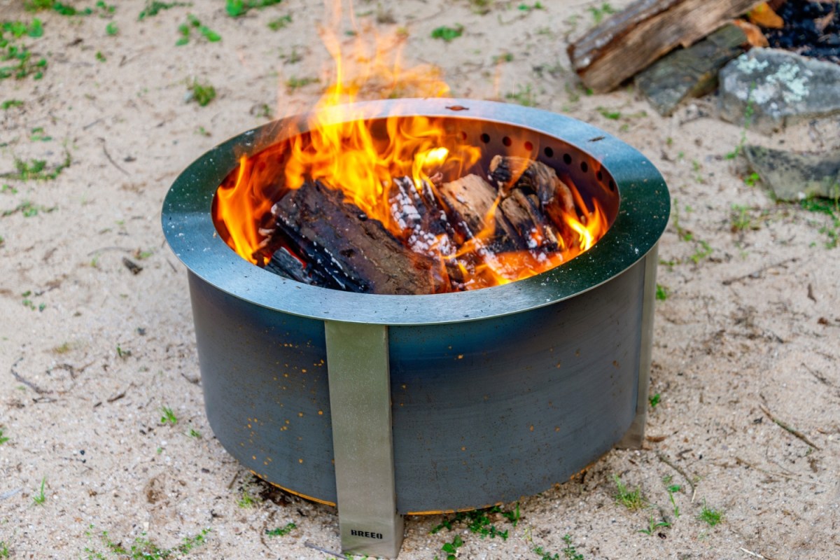 The Breeo X Series 24 Smokeless Fire Pit on sand while burning a fire during testing.