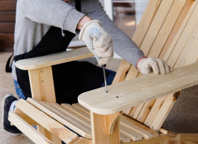 Person turning screw on Adirondack chair arm rest