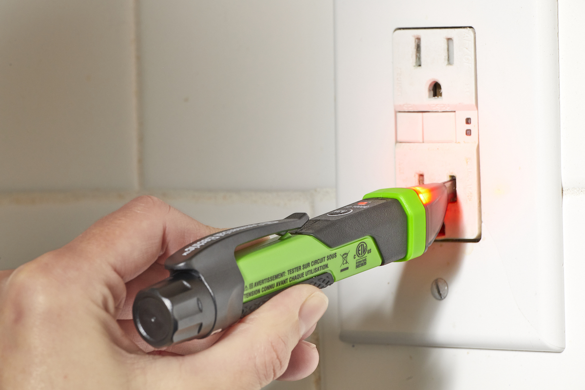 Woman uses a circuit tester in an outlet.