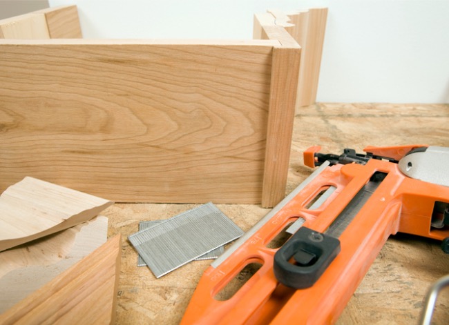 A brad nailer next to some wood molding.