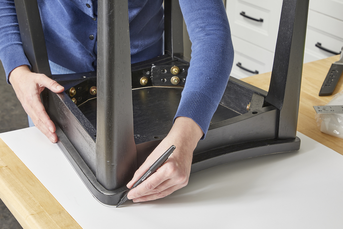 Woman tracing outline of a chair seat onto a piece of posterboard.