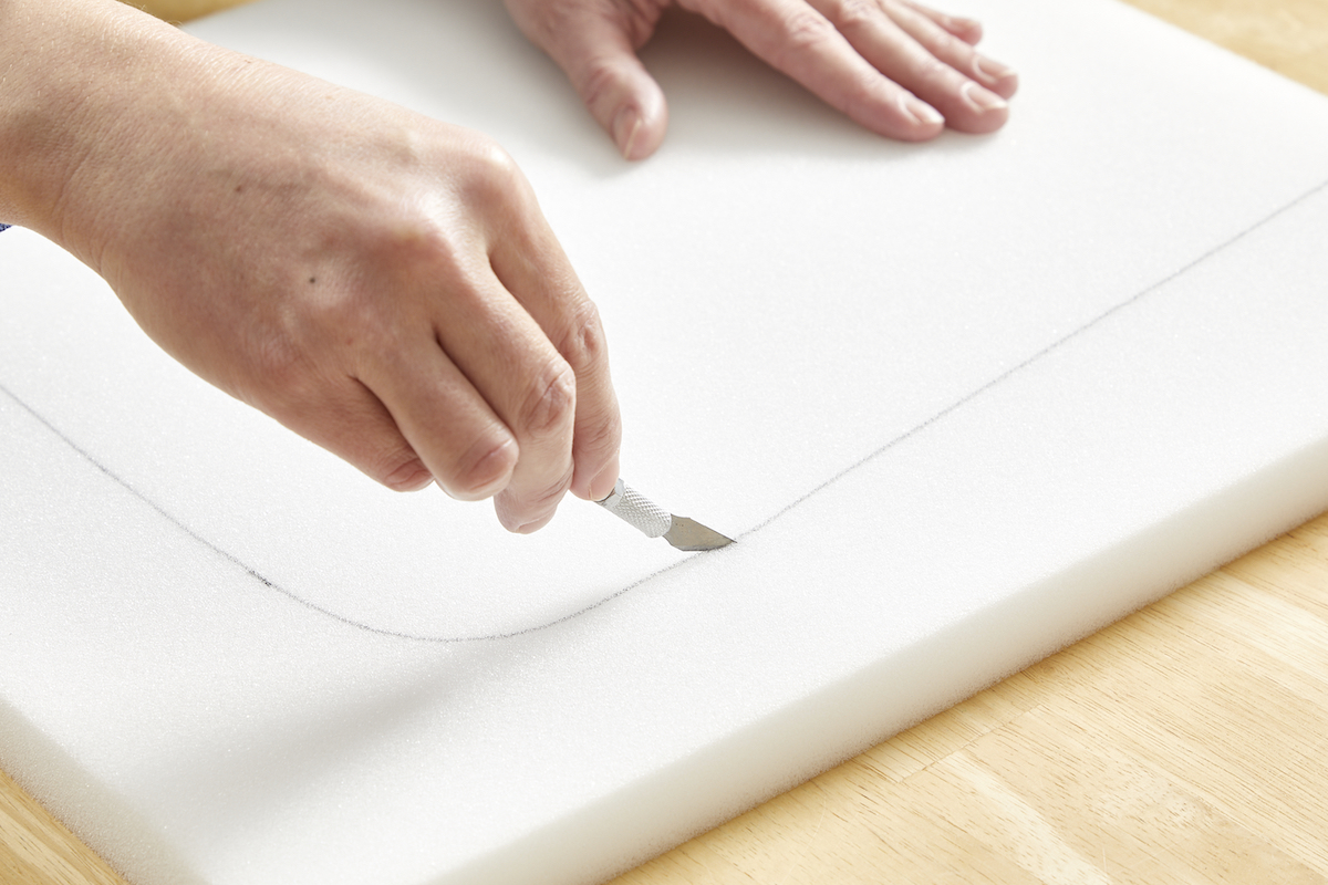 Woman cutting foam with a utility knife.