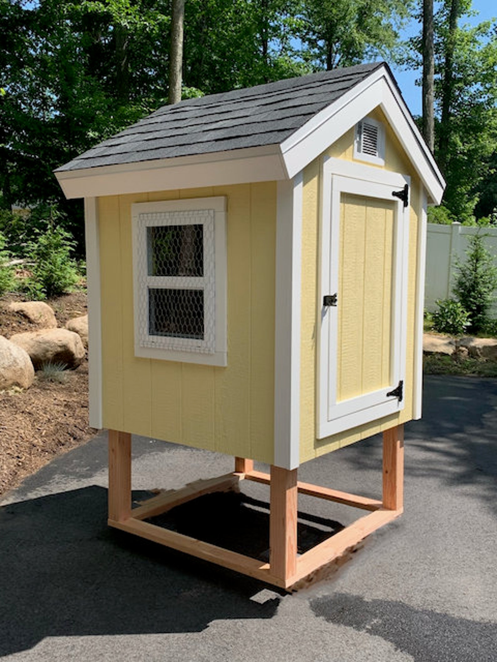 Small, cottage-style yellow chicken coop on stilts.