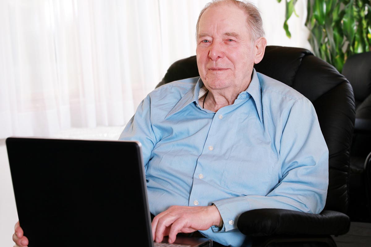 A senior sitting in the best recliner for senior while using a laptop