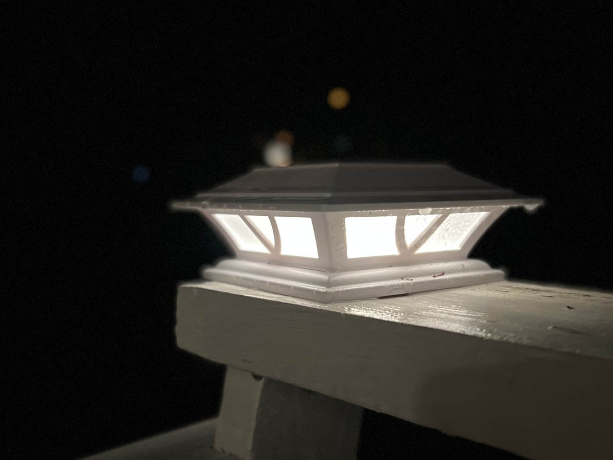 White deck light on top of a white painted wood deck illuminated at night