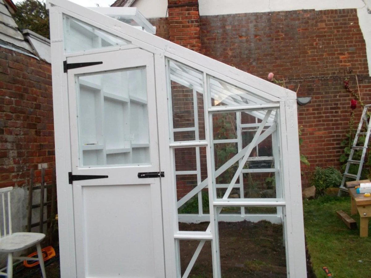 White wood and glass lean-to style greenhouse.